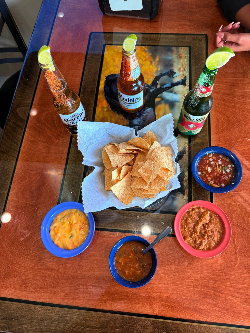 Chips and three salsas with Modelo and Corona beers on the cantina table